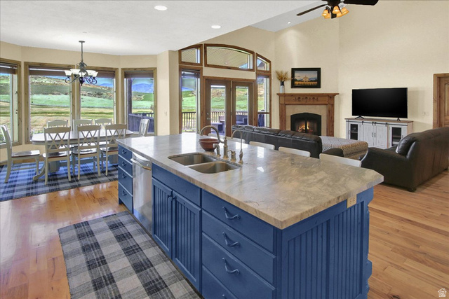 667 Hardscrabble Road Morgan, UT 84050 - Photo 50 of 51 Kitchen with blue cabinets, open floor plan, light wood finished floors, a lit fireplace, and an island with sink
