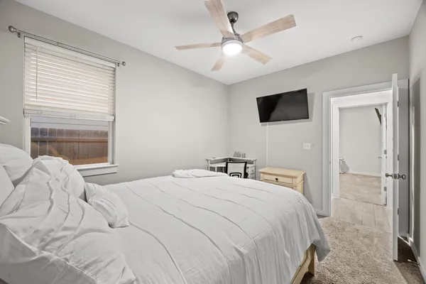 a bedroom with a bed a window and a flat screen tv