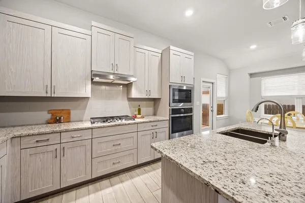 a kitchen with stainless steel appliances granite countertop a sink stove and refrigerator