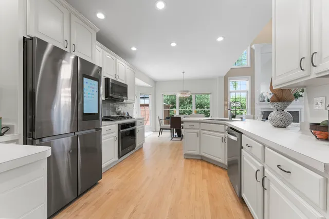 a kitchen with white cabinets and wooden floors