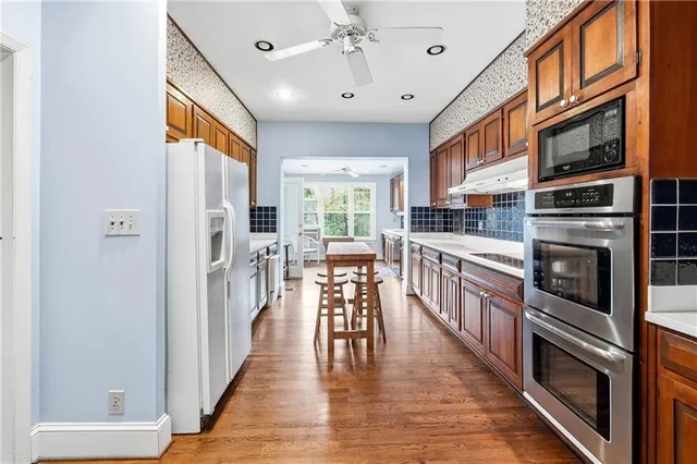a kitchen with stainless steel appliances granite countertop a refrigerator a stove and a wooden floors