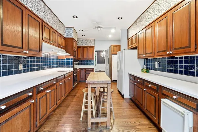 a kitchen with stainless steel appliances kitchen island granite countertop a refrigerator a stove and wooden cabinets