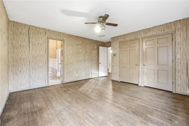 an empty room with wooden floor ceiling fan