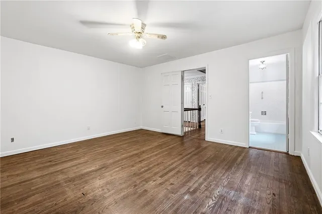 an empty room with wooden floor and ceiling fan