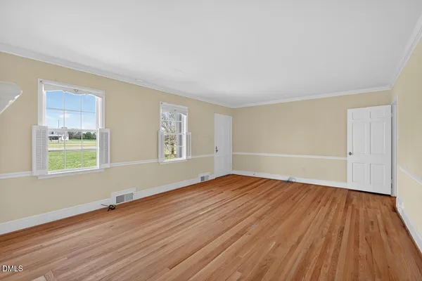 an empty room with wooden floor fireplace and windows