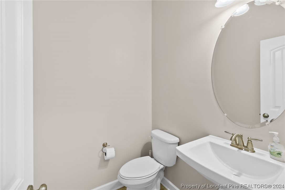 6817 Hunters Den Road Hope Mills, NC 28348 - Photo 22 of 49 a bathroom with a sink a toilet and a mirror