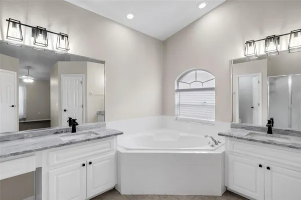 a bathroom with a granite countertop bathtub a sink and a mirror