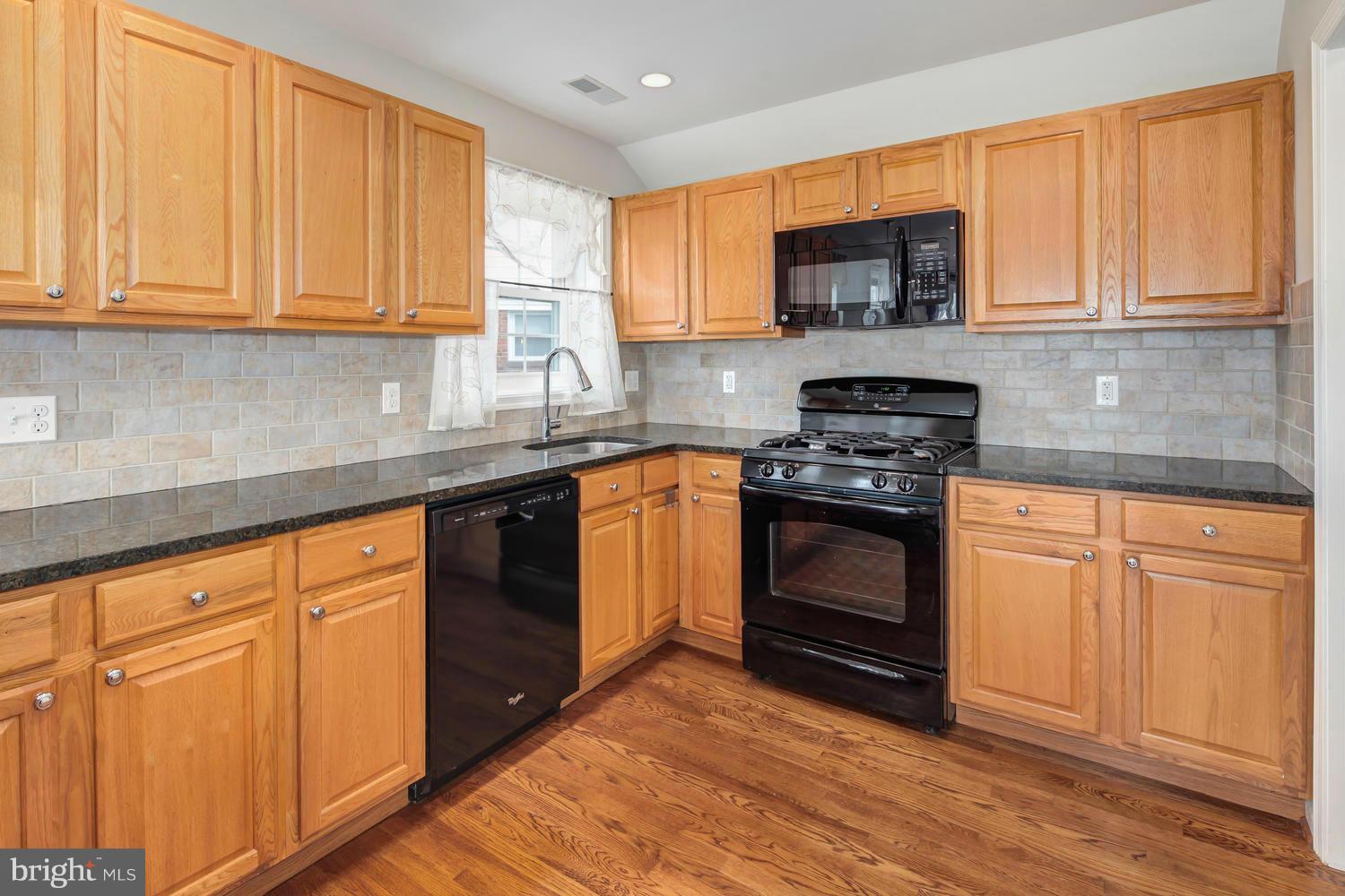 12601 Denley Road Silver Spring, MD 20906 - Photo 11 of 30 a kitchen with granite countertop wooden cabinets stainless steel appliances and a window