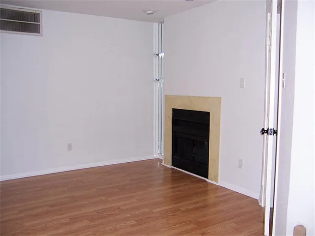 a view of an empty room with wooden floor and a fireplace