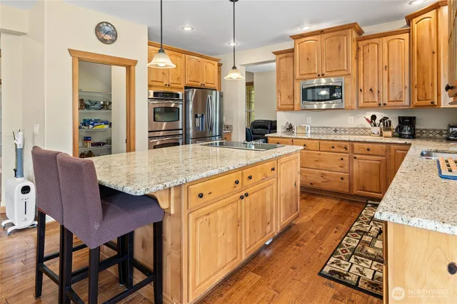 a kitchen with stainless steel appliances granite countertop a stove top oven a sink dishwasher and cabinets with wooden floor