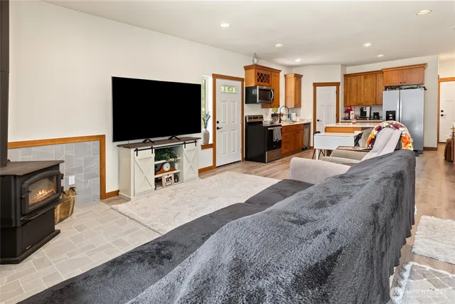 a large living room with stainless steel appliances furniture a flat screen tv and kitchen view