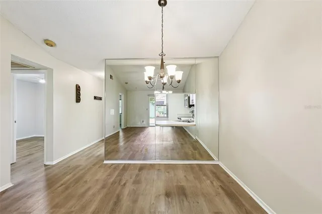 a view of a room with wooden floor chandelier and a kitchen