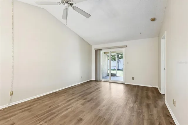 a view of an empty room with a window and wooden floor