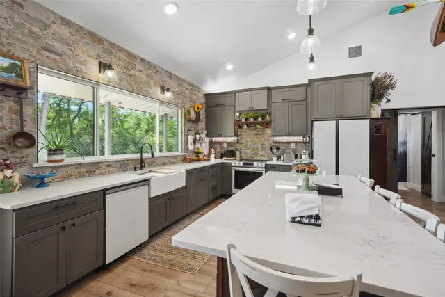 a kitchen with sink a refrigerator and chairs