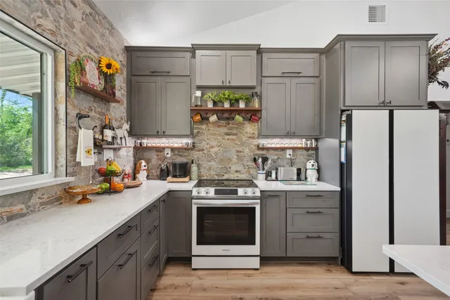 a kitchen with stainless steel appliances granite countertop a refrigerator stove and sink