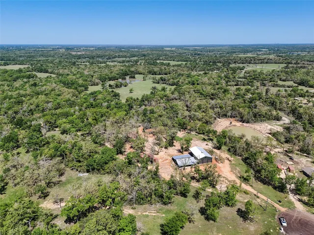 an aerial view of residential houses with outdoor space and trees