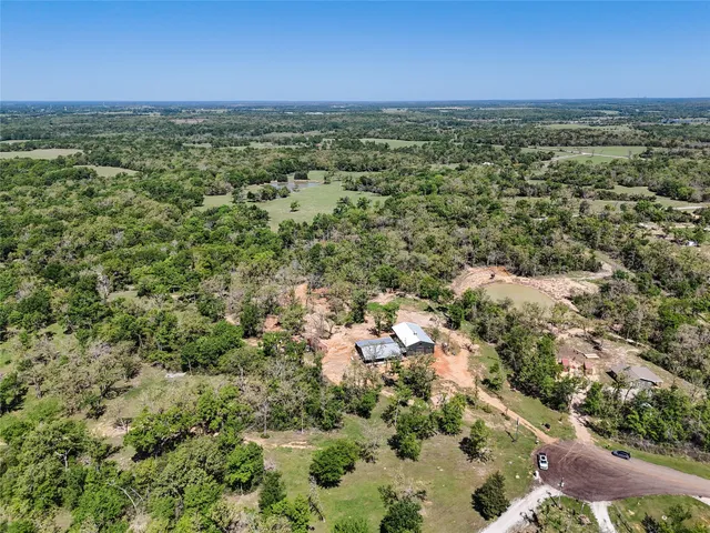 an aerial view of residential houses with outdoor space and trees