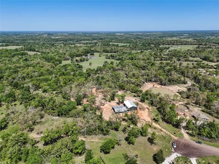 an aerial view of residential houses with outdoor space and trees