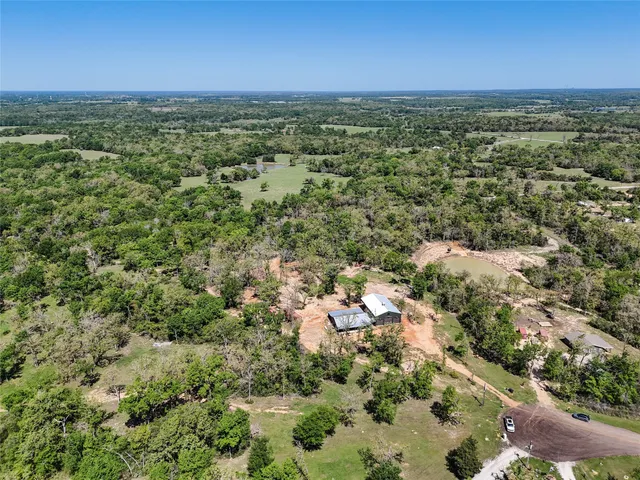 an aerial view of residential houses with outdoor space and trees
