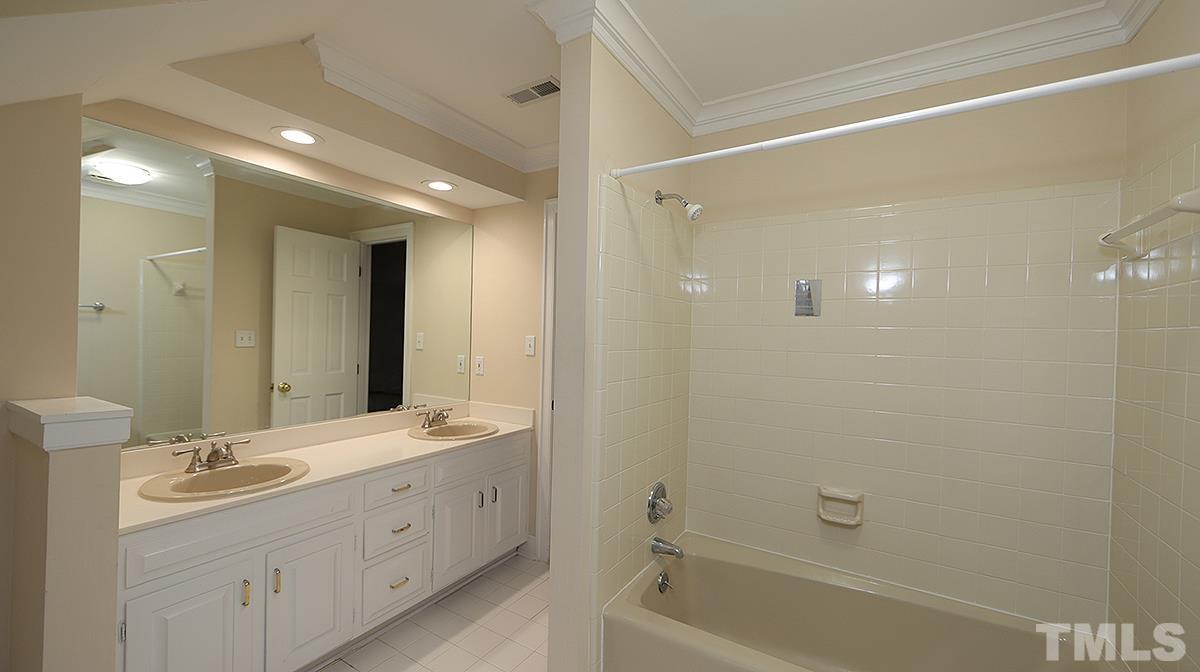 2203 Landings Way Raleigh, NC 27615 - Photo 18 of 22 a bathroom with a double vanity sink a large mirror and shower