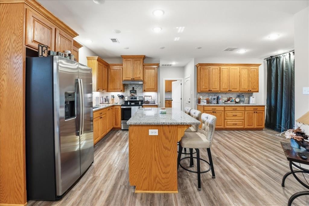 971 Bamboo Road Big Sandy, TX 75755 - Photo 31 of 40 a kitchen with stainless steel appliances granite countertop a refrigerator a sink dishwasher a stove and a dining table with wooden floor