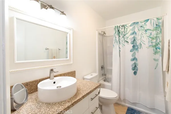 a bathroom with a granite countertop sink toilet a mirror and shower