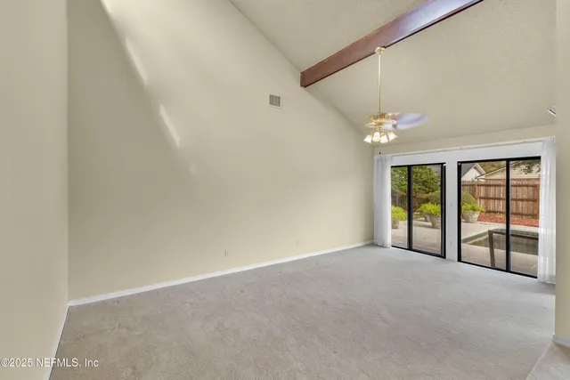 a view of an empty room with chandelier fan and fire place