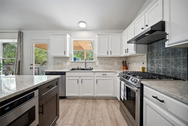 a kitchen with granite countertop stainless steel appliances a sink stove and cabinets
