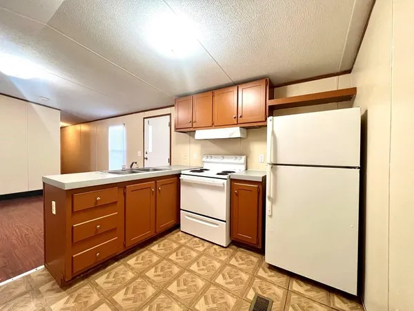 a kitchen with granite countertop a refrigerator a sink and white cabinets