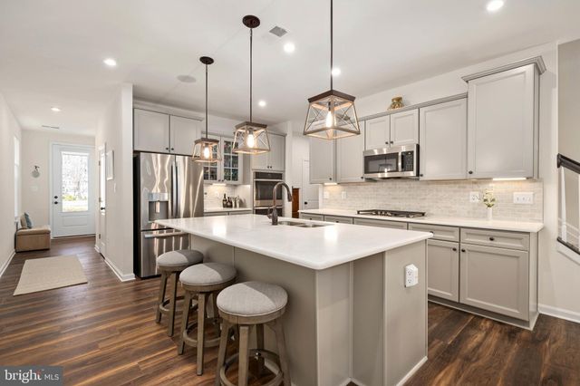 a kitchen with stainless steel appliances kitchen island granite countertop a sink a stove a refrigerator and island with wooden floor