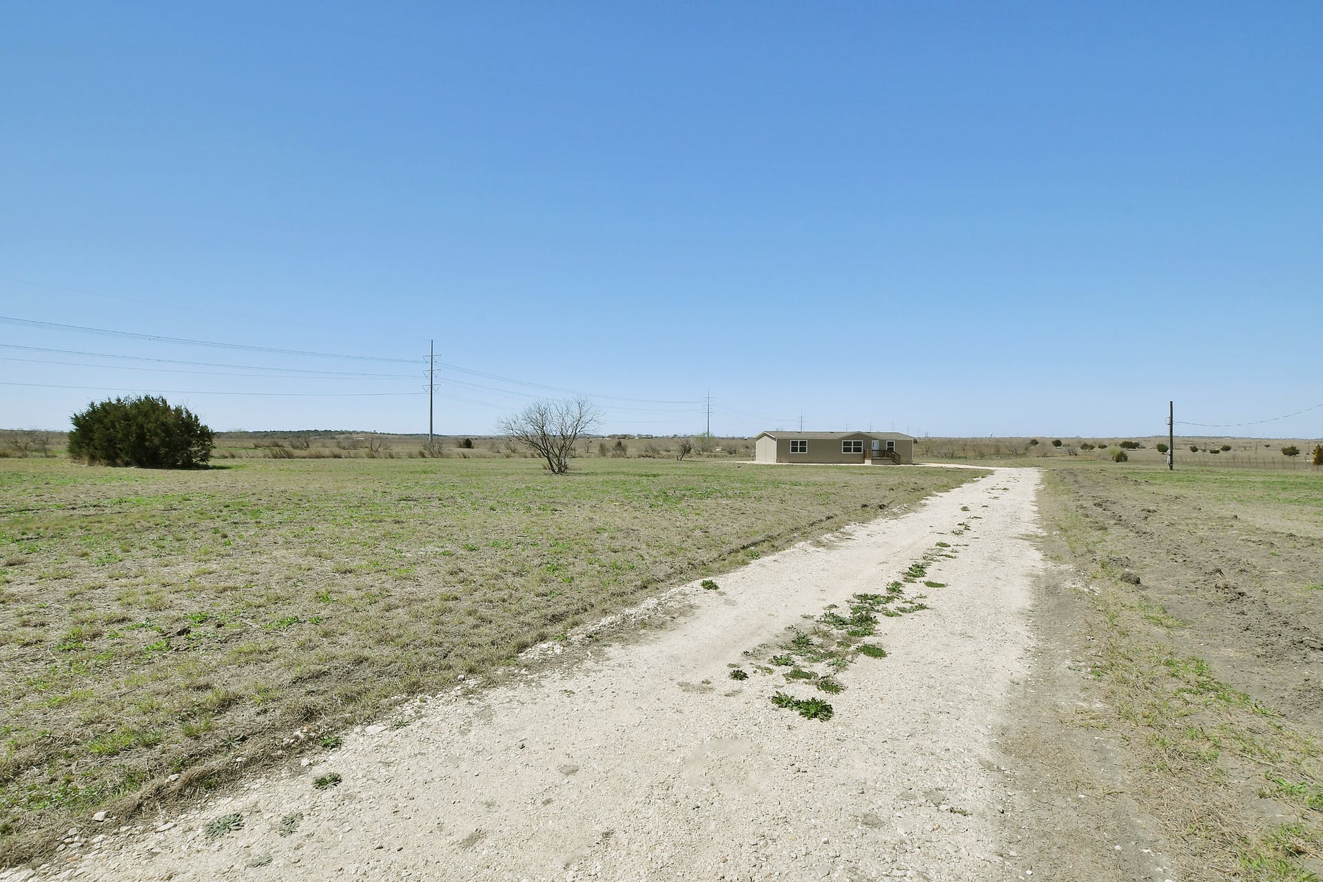 14512 Graef Road, Unit B Buda, TX 78610 - Photo 19 of 20 A long, unpaved driveway leads through vast open fields to a secluded residence.