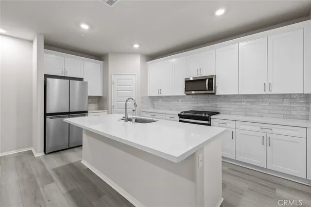 a kitchen with a sink a stove a refrigerator and white cabinets
