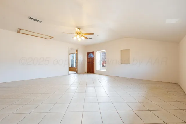an empty room with windows and fan