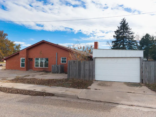 a view of a house with a yard plants and wooden fence