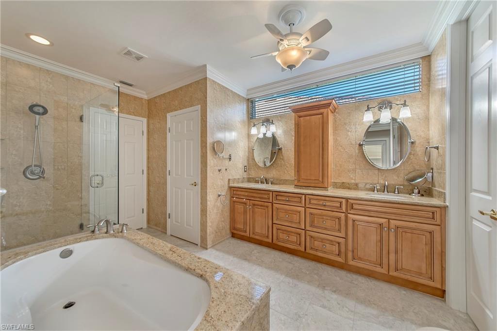 2004 Timarron Way Naples, FL 34109 - Photo 22 of 30 a spacious bathroom with a granite countertop tub sink a mirror a shower and vanity