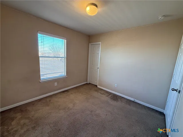 a view of an empty room with window and closet area