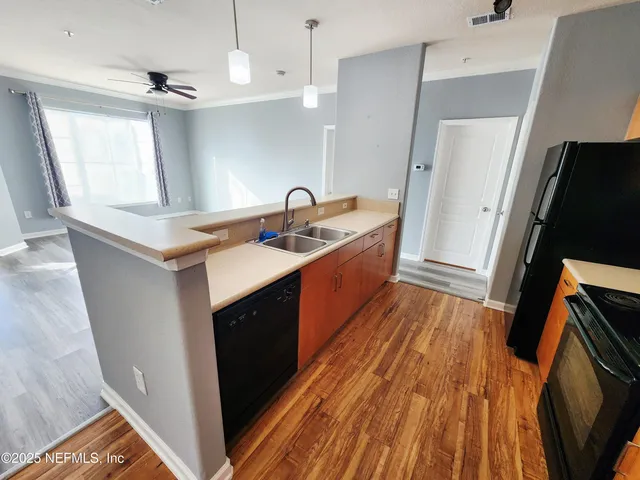 a kitchen with sink a refrigerator and wooden floor
