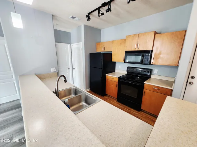 a kitchen with stainless steel appliances kitchen island granite countertop a refrigerator a stove top oven a sink and dishwasher