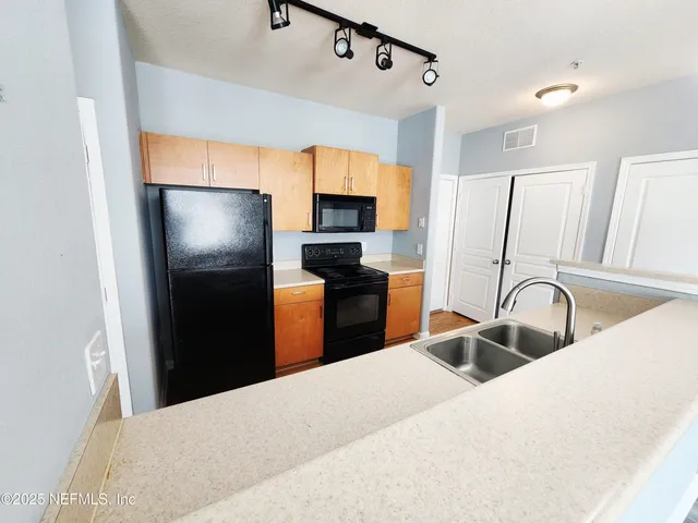 a kitchen with granite countertop a refrigerator and a sink