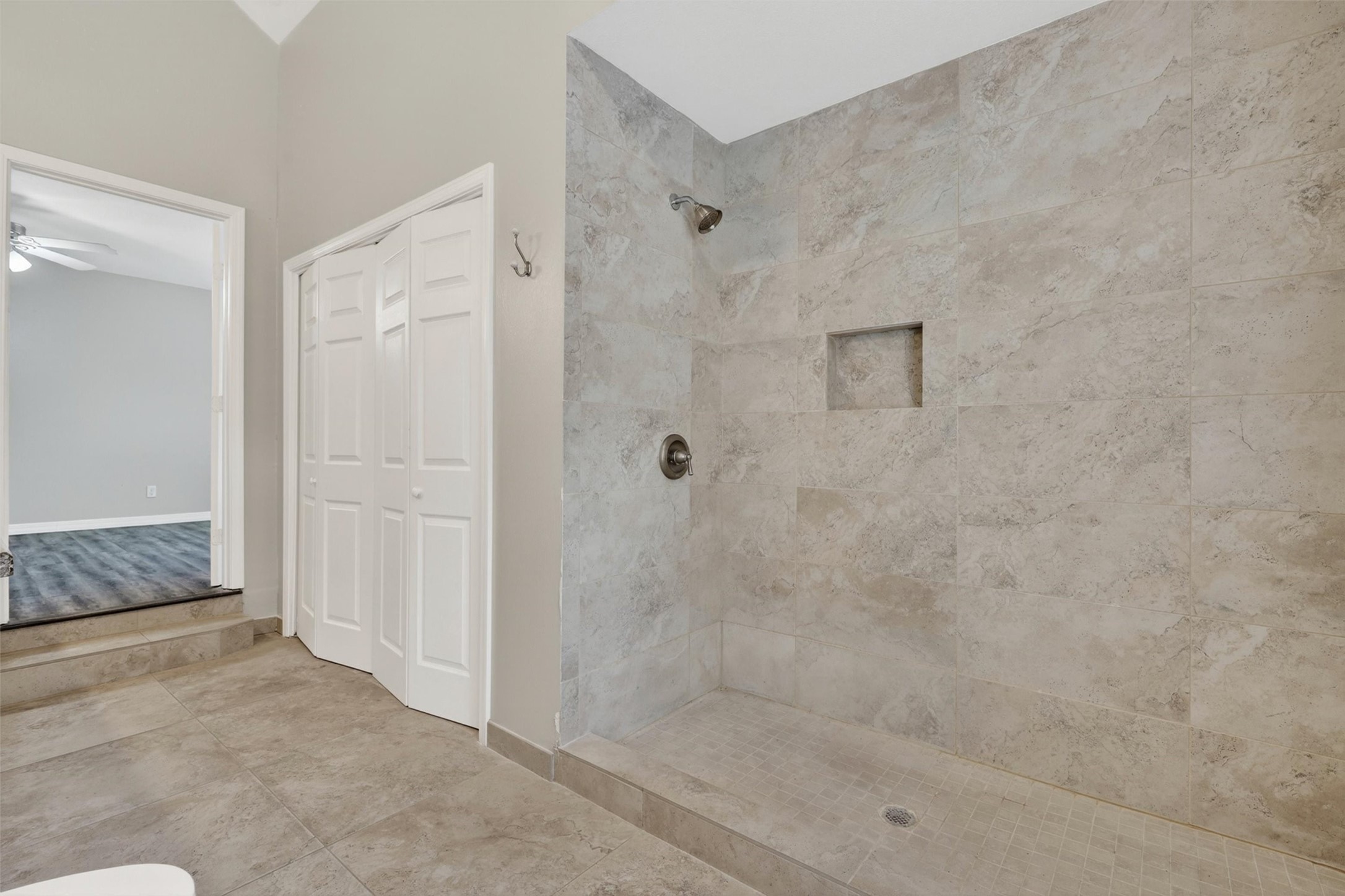 12929 Kingsbridge Lane Houston, TX 77077 - Photo 23 of 42 Relax in this spa-inspired primary bathroom featuring an oversized walk-in shower with elegant floor-to-ceiling tile, modern finishes, and a luxurious open design. Buyers will love the spacious layout, sleek built-in shower niche, and contemporary spa-like feel that creates the perfect private retreat. The high ceilings and neutral designer tones enhance the bright, airy atmosphere while adding timeless appeal.