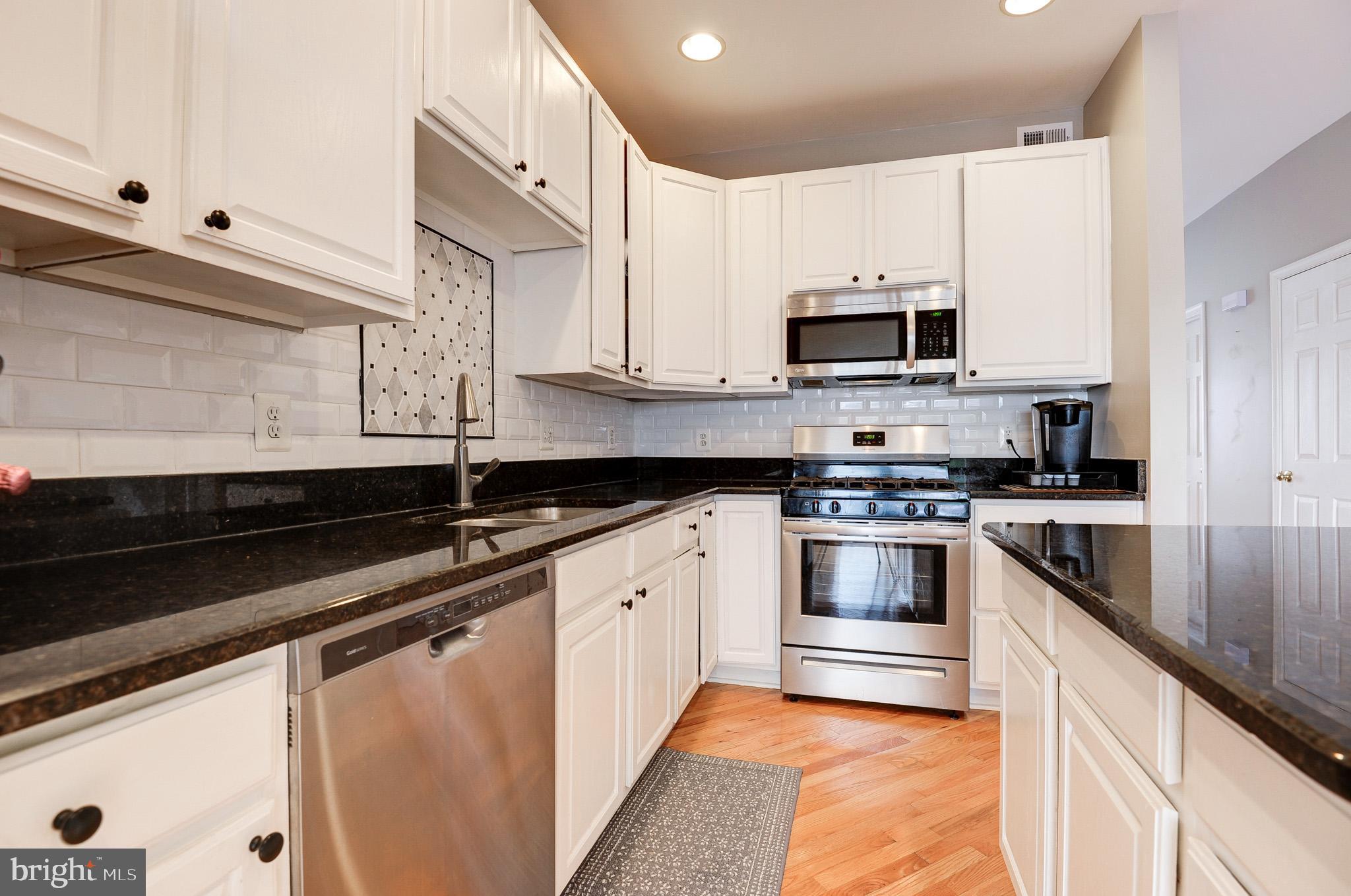 44167 Tippecanoe Terrace Ashburn, VA 20147 - Photo 11 of 56 a kitchen with granite countertop white cabinets and stainless steel appliances