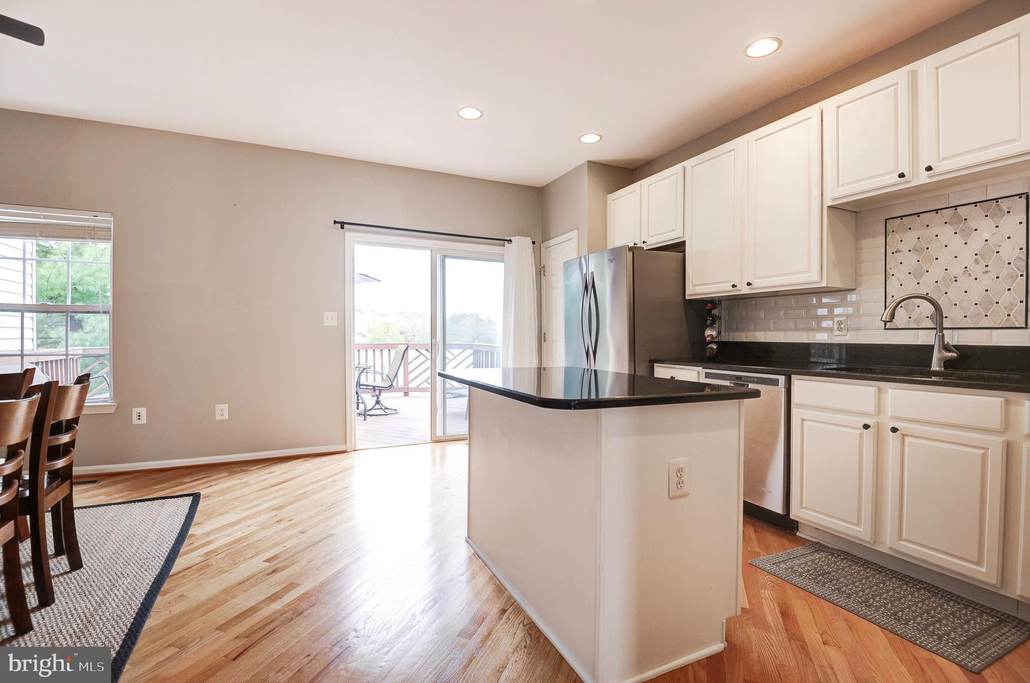 44167 Tippecanoe Terrace Ashburn, VA 20147 - Photo 9 of 56 a kitchen with granite countertop a refrigerator a sink a stove a dining table and chairs with wooden floor
