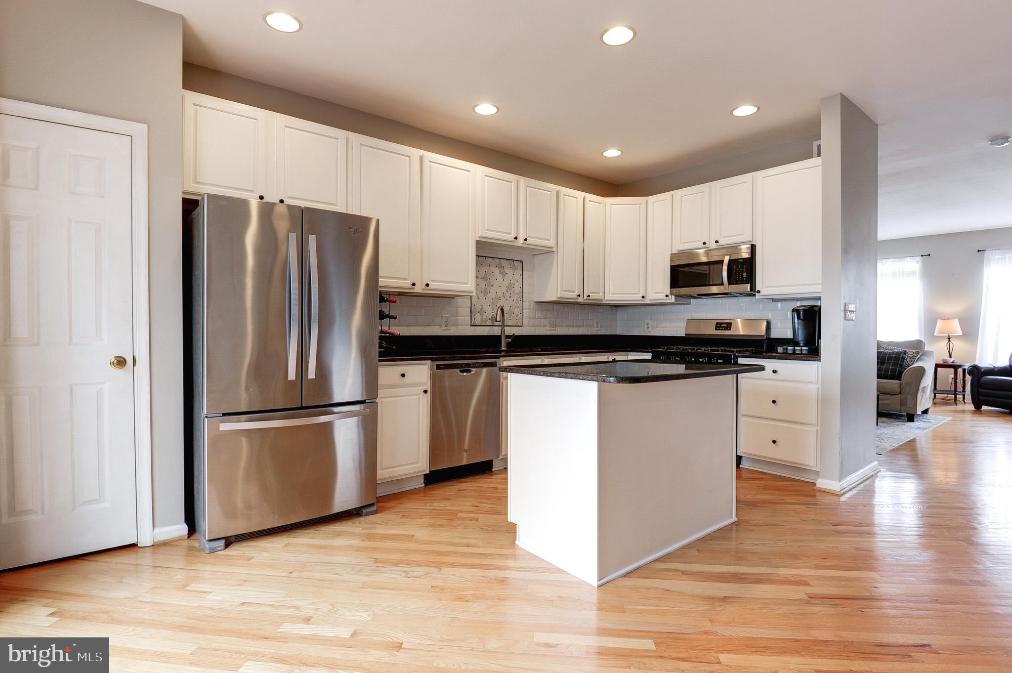 44167 Tippecanoe Terrace Ashburn, VA 20147 - Photo 10 of 56 a kitchen with kitchen island white cabinets and stainless steel appliances