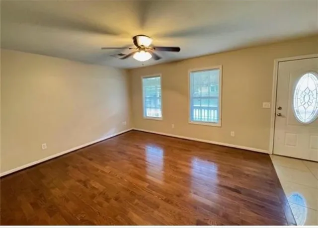 a view of an empty room with a window and wooden floor