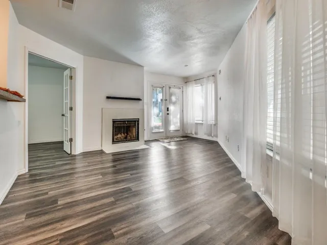a view of an empty room with wooden floor fireplace and a window