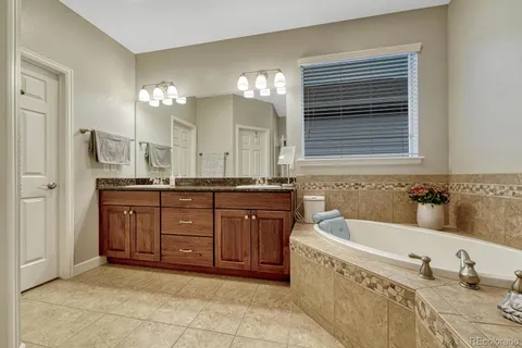 a bathroom with a granite countertop double vanity sink a bathtub and a mirror