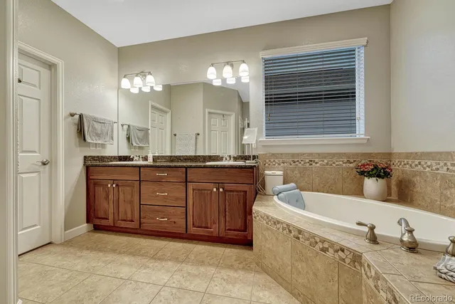 a bathroom with a granite countertop double vanity sink a bathtub and a mirror