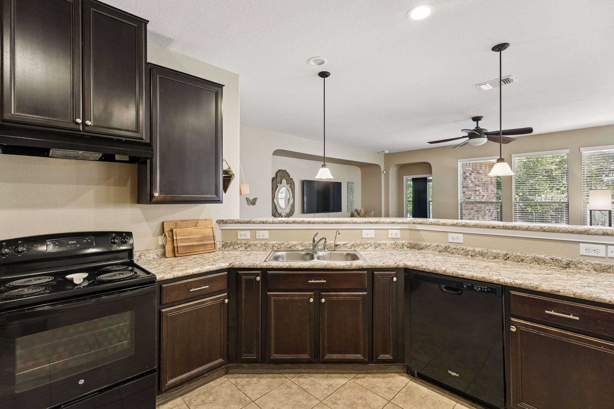 1113 Yellow Iris Road Leander, TX 78641 - Photo 9 of 26 Rich dark cabinetry and stone-look countertops anchor an open kitchen overlooking the living spaces.