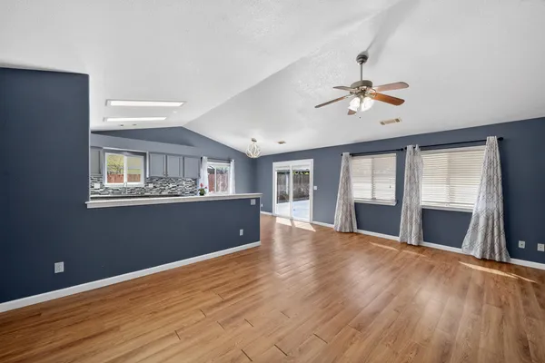 a view of an empty room with window and wooden floor