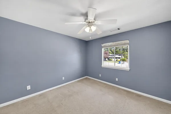 an empty room with a window and a fan